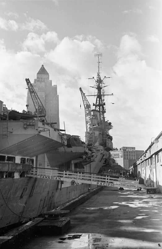 The Marine Building looking over the British aircraft carrier HMS Glory in 1945. Photo by James Crookall, City of Vancouver Archives #260-1537.