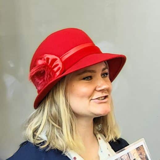 Rachel Ruecker, woman in a bright red hat with blonde hair hosting a tour