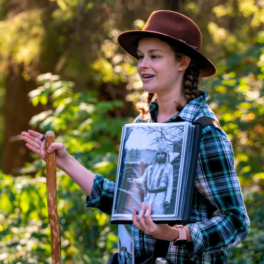 A photo of the guide in Stanley Park holding a walking stick and showcasing a history photo
