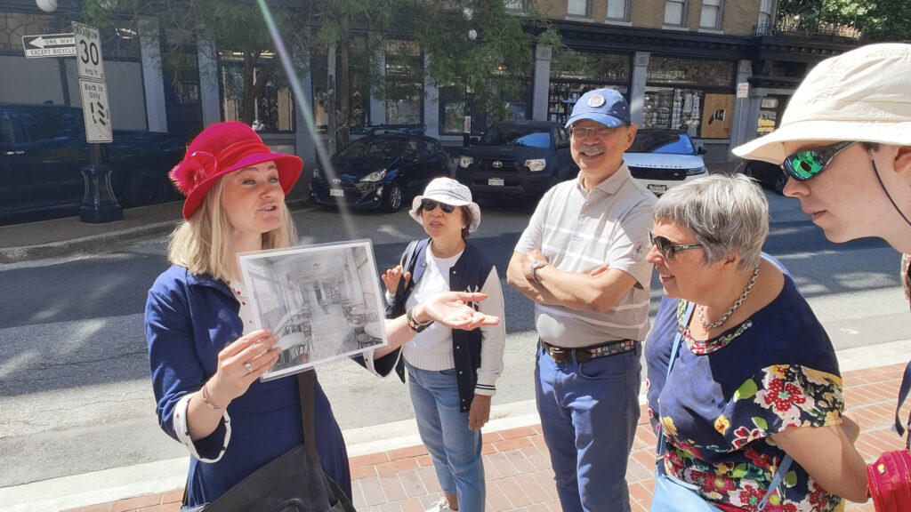 Tourguide shows guests a photo from Vancouver's past as they lean into