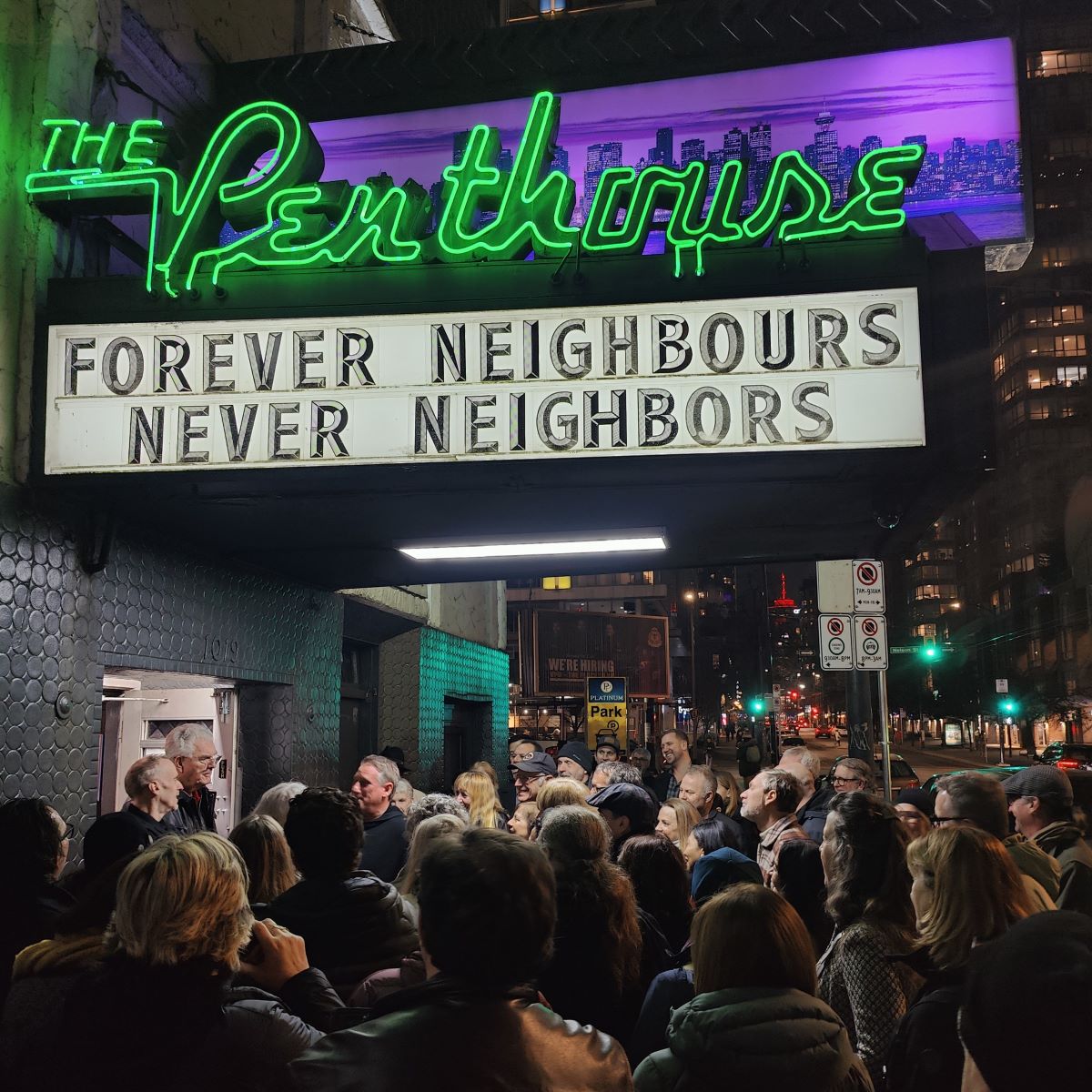 10 Actually Fun Things To Do In Vancouver for Young Adults 3 A green neon sign that reads "The Penthouse." Underneath it, a marquee that reads "Forever Neighbours, Never Neighbors." A crowd of people stand below the marquee.